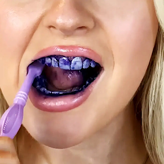 Purple teeth color corrector serum being applied with a toothbrush